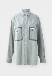 Camicia oversize a righe in cotone azzurro chiaro, con due tasche sul petto con dettagli in denim, chiusura con bottoni e maniche lunghe con particolari ai polsini.