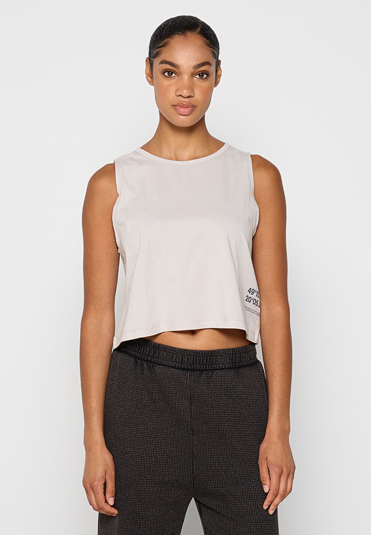 Jasnoszara krótka bluzka na ramiączkach z okrągłym dekoltem, bez rękawów, z czarnym napisem na dole. Wykonana z miękkiego materiału, o luźnym kroju.