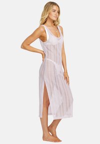 Langes, lavendelfarbenes, offen gestricktes Überwurfkleid mit breiten Trägern, seitlichen Schlitzen und lockerer Passform, das eine transparente Textur zeigt.