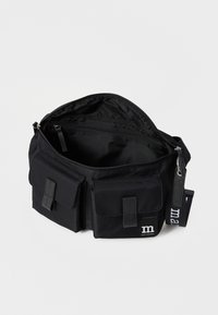 Borsa a tracolla nera realizzata in tessuto resistente, con un compartimento principale con zip, due tasche frontali e una tracolla removibile.