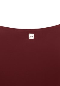 Tessuto bordeaux con una texture liscia e un piccolo etichetta crema con la scritta "Manila Grace" attaccata al centro superiore.