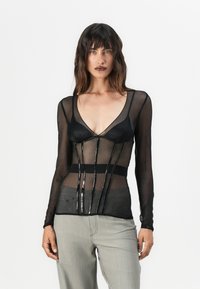 Svart mesh langermet topp med gjennomsiktig stoff, v-hals og dekorative vertikale paneler. Fitted midje med teksturerte detaljer.