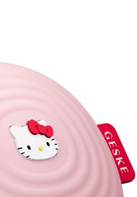 Rosa silikongryta med koncentriska ringar, med ett vitt Hello Kitty-ansikte och röd rosett. Röd handtag med texten "GESKE".