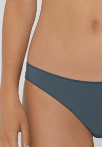 Dunkelblaue Bikini-Hose aus glattem Stoff, mit einem low-rise Design und minimaler Seitenabdeckung sowie genähten Kanten.