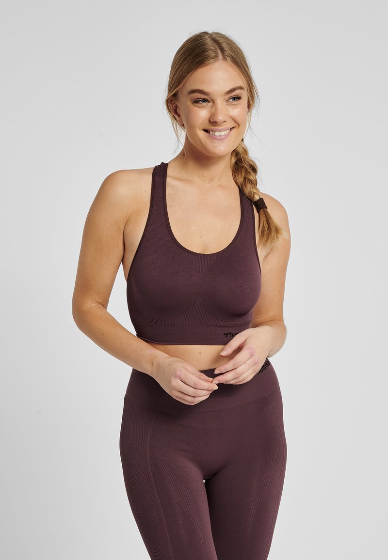 Bordeauxrode sportbeha met een ronde halslijn, brede bandjes en een nauwsluitend ontwerp. De stof heeft een geribbelde textuur voor extra ondersteuning.