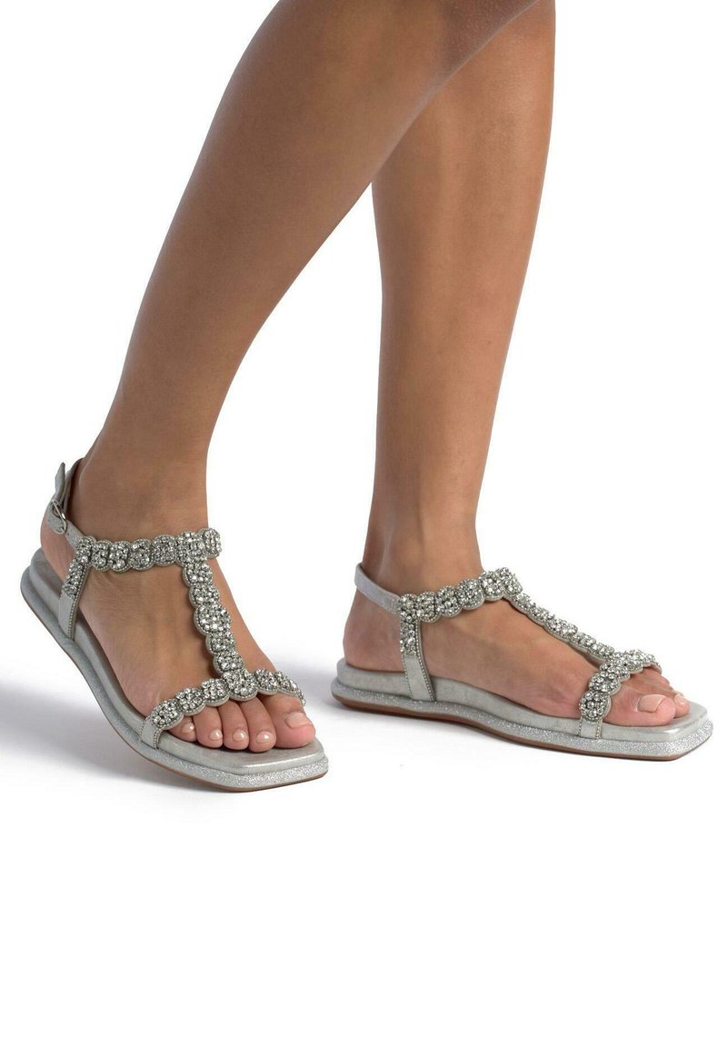 Zilveren sandalen met een T-bandontwerp, versierd met heldere edelstenen, platte zool en verstelbare enkelband, die een textuurfinish laat zien.