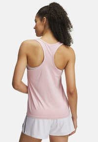 Top sportivo senza maniche di colore rosa con design a racerback, texture liscia e dettagli di cuciture a contrasto. Indossato con pantaloni corti bianchi.
