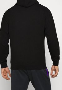 Felpa con cappuccio nera a maniche lunghe, realizzata in tessuto morbido, con orlo e polsini a coste, e un design semplice e pulito.