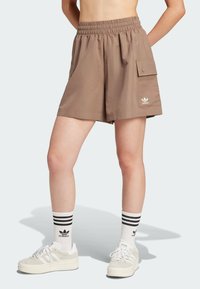Brown, knee-length shorts with an elastic waistband, side pockets, and an accent pocket on the leg. Paired with white sneakers and striped socks.