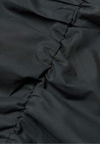 Tessuto nero con una texture liscia, caratterizzato da sezioni arricciate che creano un effetto plissettato. Il materiale è leggero e morbido.