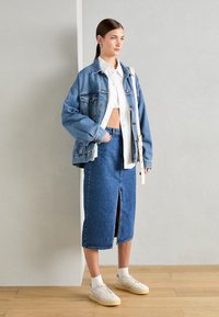 Denim oversized jacka, vit kort skjorta, högmidjad denimkjol med framfålla, parat med lätta sneakers och vita strumpor.