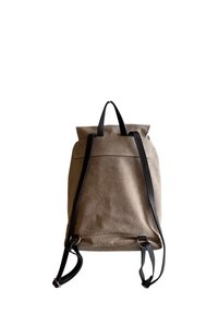 Hnědý semišový batoh s černými koženými popruhy, designem na rolovací uzávěr a jednoduchým, čistým stylem. Má hladký povrch a minimální kovové doplňky.