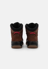 Braune Wildleder-Ankle Boots mit schwarzen Gummisohlen, gepolstertem schwarzen Kragen und rotem Logoakzent an der Ferse. Mit strukturiertem Finish.