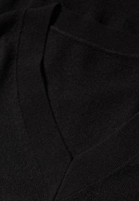 Czarny sweter z dzianiny z dekoltem w serek, miękką teksturą i widocznymi szwami, prezentujący gładkie wykończenie tkaniny z subtelnymi detalami.