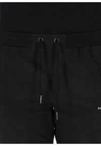 Pantaloni corti da jogging neri con vita elastica, cordino con occhielli in metallo e dettaglio del logo laterale. Texture del tessuto liscia.