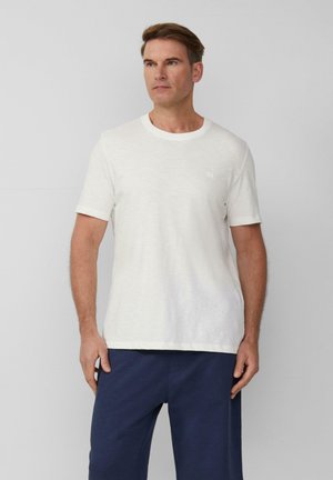 Witte t-shirt met korte mouwen van een gestructureerde stof, ronde halslijn, voorzien van een klein logo op de linkerborst, gecombineerd met marineblauwe pantalons.