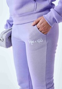 Paarse sweatpants met een naadloos ontwerp, voorzien van een zijzak en geborduurd "Project x Paris" logo in het wit. Zacht, gestructureerd stof.