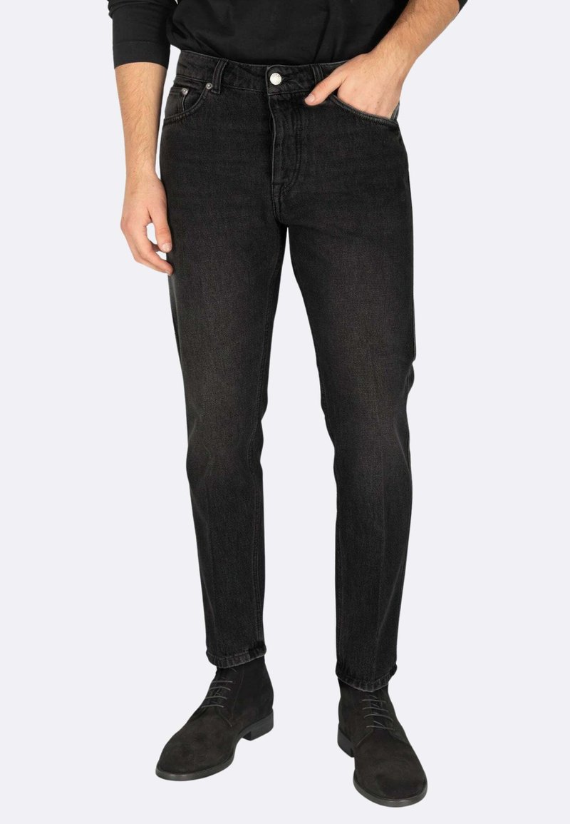 Jeans in denim nero con una silhouette slim fit, design a cinque tasche e chiusura con bottone metallico. Indossati con stivaletti alla caviglia in suede scuro.