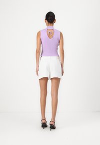 Lilac ribbed sleeveless top with a back keyhole detail, paired with white denim shorts featuring a frayed hem and two back pockets. Black heeled sandals.