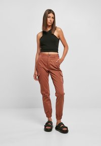 Svart kortärmad tanktopp, bruna cargobyxor med elastiska muddar och sidofickor, ihop med svarta sandaler med en tjock remdesign.
