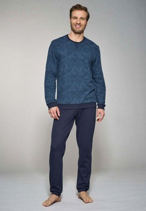 Maglietta a maniche lunghe blu navy con motivo, colletto a girocollo e dettaglio dei bottoni, abbinata a pantaloni della tuta blu navy uniti. Entrambi realizzati in tessuto morbido.
