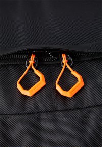 Black fabric bag featuring a smooth texture, with an orange hexagonal zipper pull and matching laces, emphasizing durability and design.