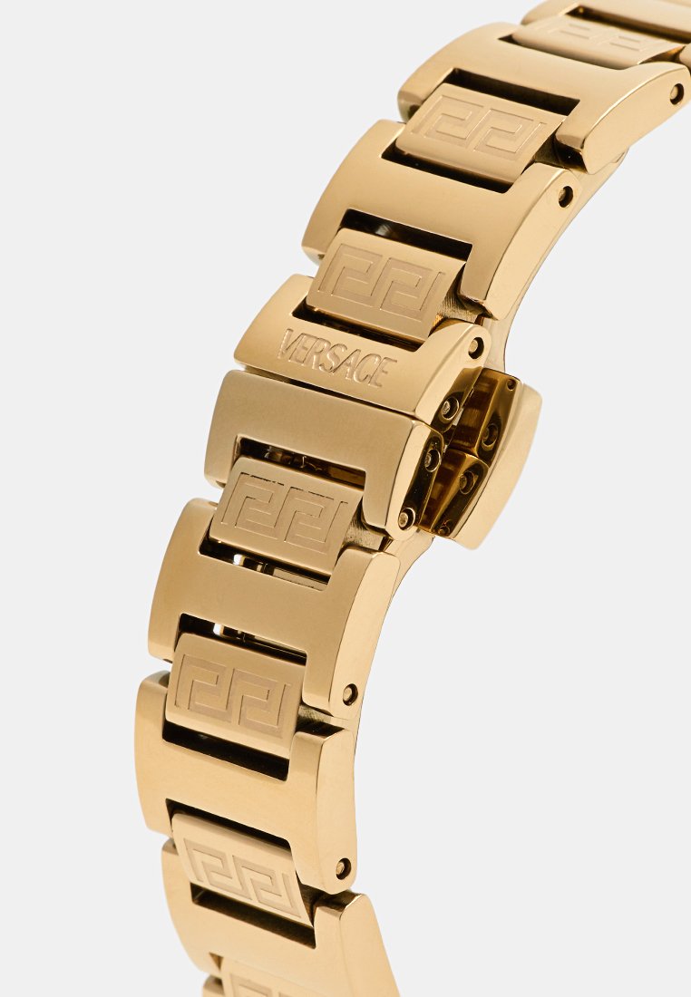 Gouden armband met een schakelontwerp en gegraveerde vierkante patronen. Duidelijk gemarkeerd met "VERSACE" op één segment. Gladde metalen textuur.