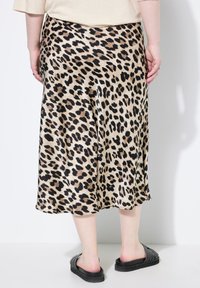 Leopardprint satijnen midi-rok, met een zachte textuur, hoge taille en vloeiende silhouet, gecombineerd met zwarte instapsandalen.