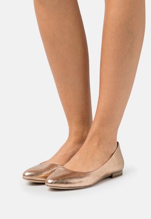 Ballerines en rose doré métallique avec un bout arrondi, texture lisse et design minimaliste. Dotées d'un petit talon plat pour le confort.