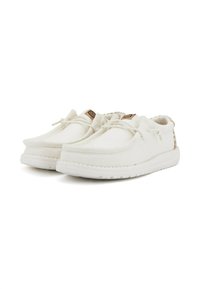 Scarpe di tela bianche con design a punta arrotondata, superficie testurizzata, chiusura senza lacci e suola in gomma leggera. Accento marrone sul tallone.