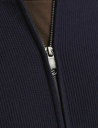 Marinblå zip-jacka med texturerad tyg och silverfärgad metalldragkedja. Inre lager i brun bomull. Har ribbat mönster och tättsittande passform.