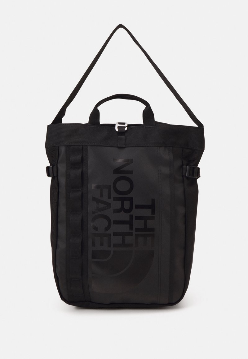 Sac cabas noir The North Face avec poignée supérieure, bandoulière réglable, sangles latérales avec boucles et logo vertical sur le panneau avant.