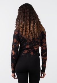 Fekete, hosszú ujjú pulóver barna tye-dye mintázattal, bordázott mandzsettákkal és rövidített fazonnal. Puha textúra, testhez simuló sziluett.