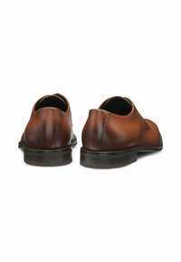 Chaussures en cuir marron à finition lisse, au design arrondi et avec des détails de couture subtils, dotées d'une semelle noire robuste et d'un faible talon.