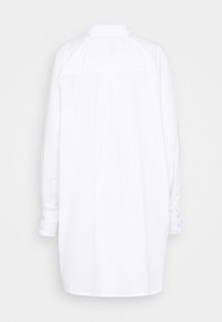 Hvid langærmet skjorte med knaplukket manchet, krave og detalje med læg bagpå. Glat stof med et enkelt, rent design.