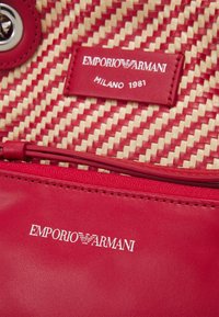 Czerwona skórzana torebka z plecionym wzorem ze słomy. Posiada wyraźną metkę z logo, srebrne akcesoria i gładkie zamknięcie na zamek.