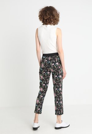 Pantaloni a fantasia floreale neri con fiori rosa e blu, con un design aderente e vita elastica; abbinati a un top bianco senza maniche.
