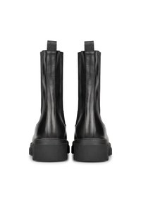 Botas de tobillo de cuero negro con paneles laterales elásticos, suelas de goma planas y dos lengüetas para facilitar el calzado. Textura suave, diseño elegante.