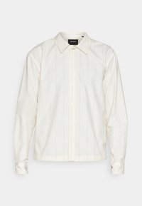 Camicia bianca a maniche lunghe con bottoni, caratterizzata da sottili righe verticali, un colletto classico e un logo ricamato sul petto. Tessuto a trama liscia.