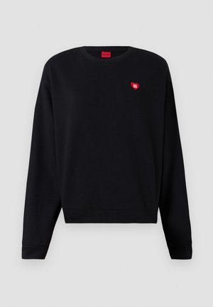 Svart sweatshirt i ett mjukt material med rundad halsringning och ribbade ärmmuddar. Har en liten röd hjärtlogotyp på bröstet.