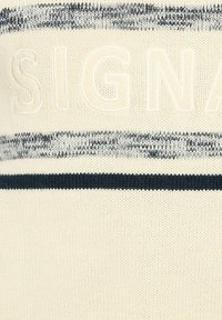 Krém színű kötött pulóver kék vízszintes csíkokkal és domború "SIGN" felirattal. Puha tapintású, laza dizájn, amely alkalmas rétegezésre.
