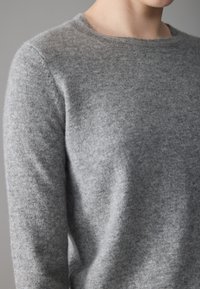 Gray wool sweater with a rounded neckline, ribbed edges, and a soft, slightly textured finish. Long sleeves are fitted and seamless.