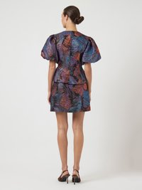 Φόρεμα με κοντά μανίκια και φουσκωτά μανίκια, διαθέτοντας ένα πολύχρωμο αφηρημένο μοτίβο σε αποχρώσεις μωβ, μπλε και πορτοκαλί σε σκούρο φόντο.