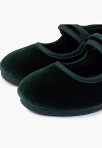 Zielone aksamitne buty z zaokrąglonym noskiem i paskiem na podbiciu. Miękka faktura i kontrastowe przeszycia na krawędziach.