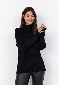 Schwarzer gerippter Rollkragenpullover mit langen Ärmeln, aus einem strukturierten Stoff und im lässigen Schnitt, kombiniert mit schwarzen Lederhosen.