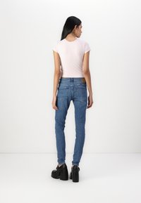 Camiseta ajustada de color rosa claro, jeans ajustados azules y zapatos de plataforma negros. El conjunto presenta un diseño simple y un estilo casual.