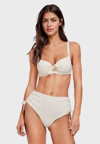 Lichtbeige bikini van gestructureerde stof met een subtiel patroon. De bh-top heeft een knoop aan de voorkant en de hoge taille onderkant heeft zijstrikjes.