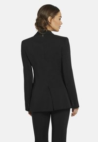 Zwarte op maat gemaakte blazer met een gestructureerde vorm, notch-kraag en enkele achteropening. De stof is glad en heeft knoopmanchetten.