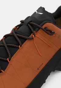 Juodi ir oranžiniai batai su tekstūruota odine viršute, pažymėti Gore-Tex logotipu, su raštuotais raišteliais ir tvirta gumine padu.