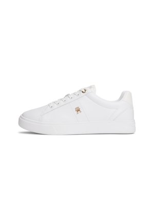 Biały niski sneaker ze sznurowadłami, złotymi oczkami i małym złotym logo po boku, pokazany od zewnętrznej strony.